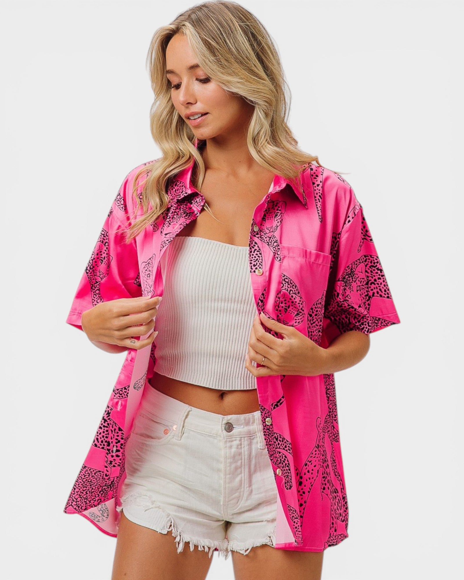 Woman wearing a bright pink shirt with leopard print accents on a white background
