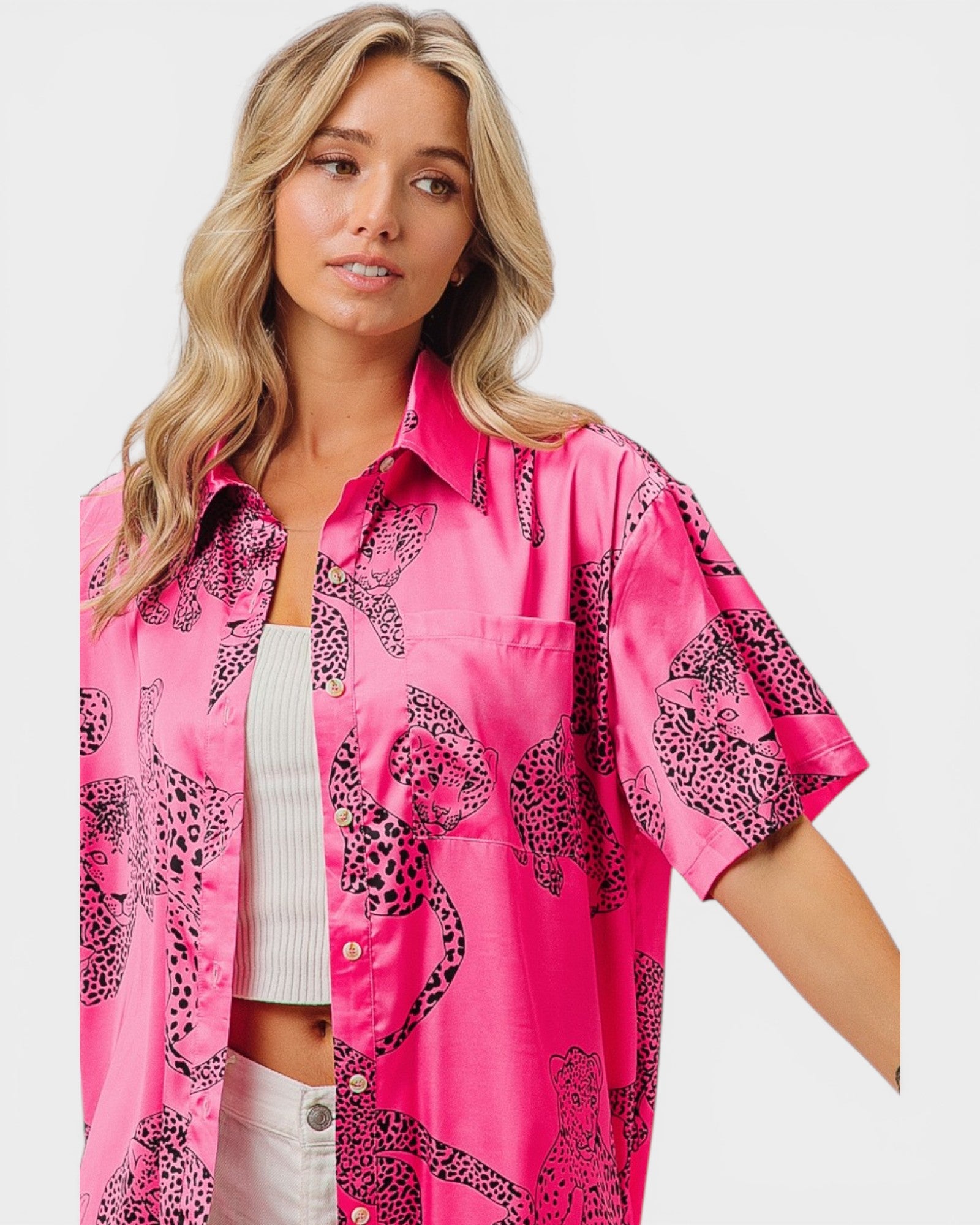 Woman wearing a pink shirt with black animal print on a white background