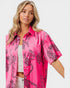 Woman wearing a pink shirt with black animal print on a white background