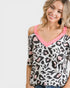 Woman wearing a leopard print top with pink trim on a white background