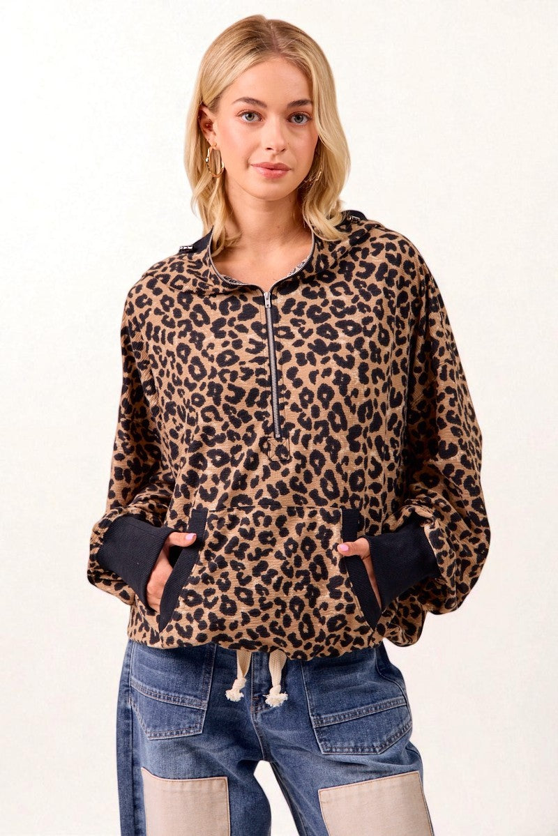 Woman wearing a leopard print hoodie and blue jeans on a white background
