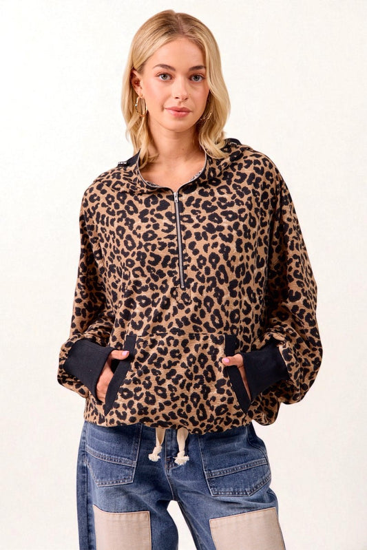 Woman wearing a leopard print hoodie and blue jeans on a white background