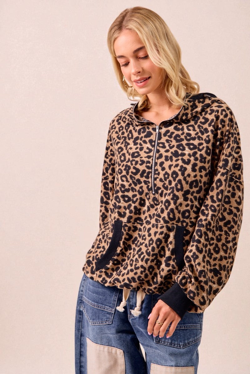 Woman wearing a leopard print hoodie with blue jeans on a beige background