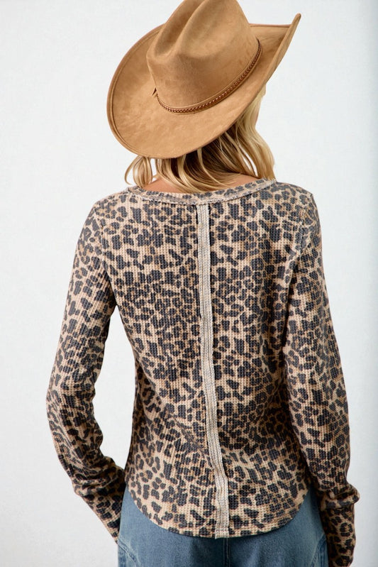 Person wearing a leopard print top and brown hat on a white background