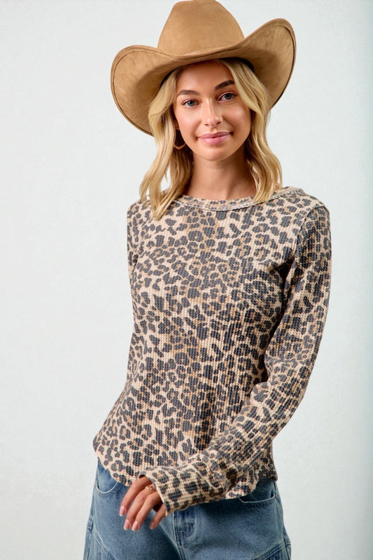 Woman wearing a leopard print top and brown cowboy hat against a white background