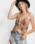 Woman wearing a leopard print top and denim shorts with a black hat on a white background
