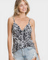 Woman wearing a leopard print camisole top and denim shorts on a plain background