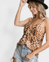 Woman wearing a leopard print top and denim shorts with a black hat on a white background