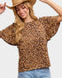 Woman wearing a leopard print top and cowboy hat on a plain background