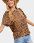 Woman wearing a leopard print top and denim shorts on a plain background