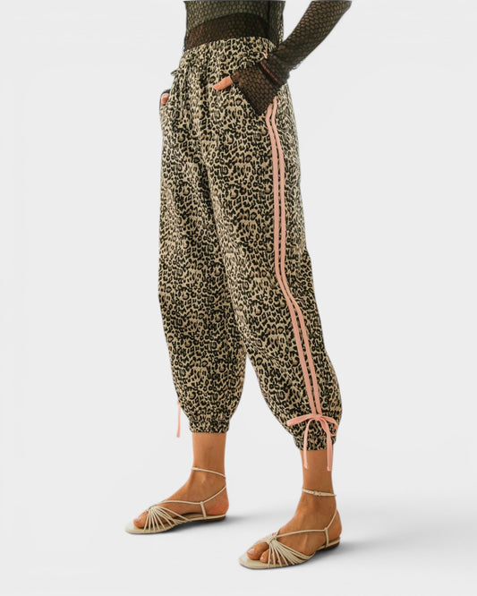 Leopard print pants with pink stripes worn by a person on a white background