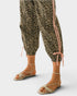 Leopard print pants with pink drawstrings worn by a person on a white background