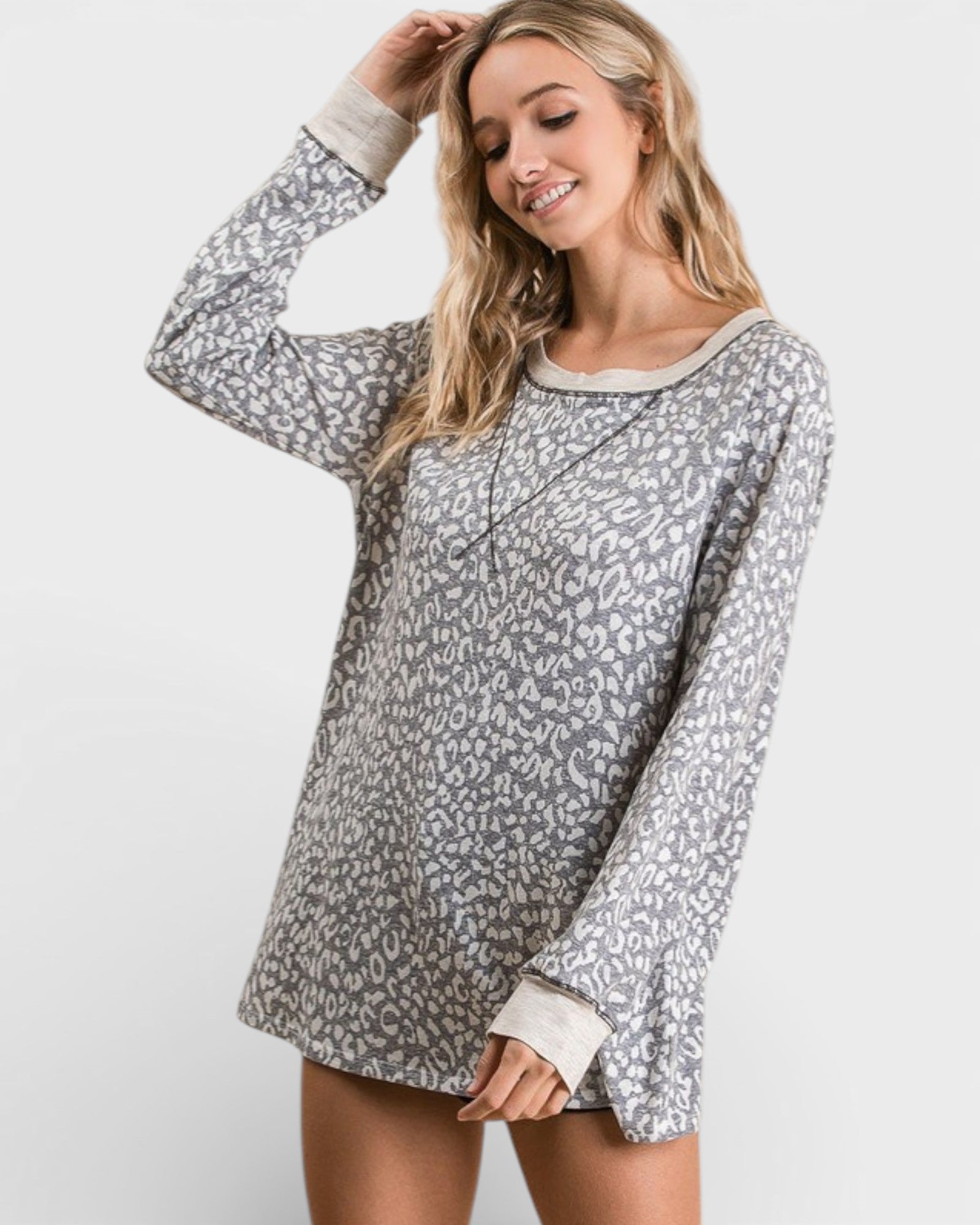 Woman wearing a gray leopard print dress with long sleeves on a white background