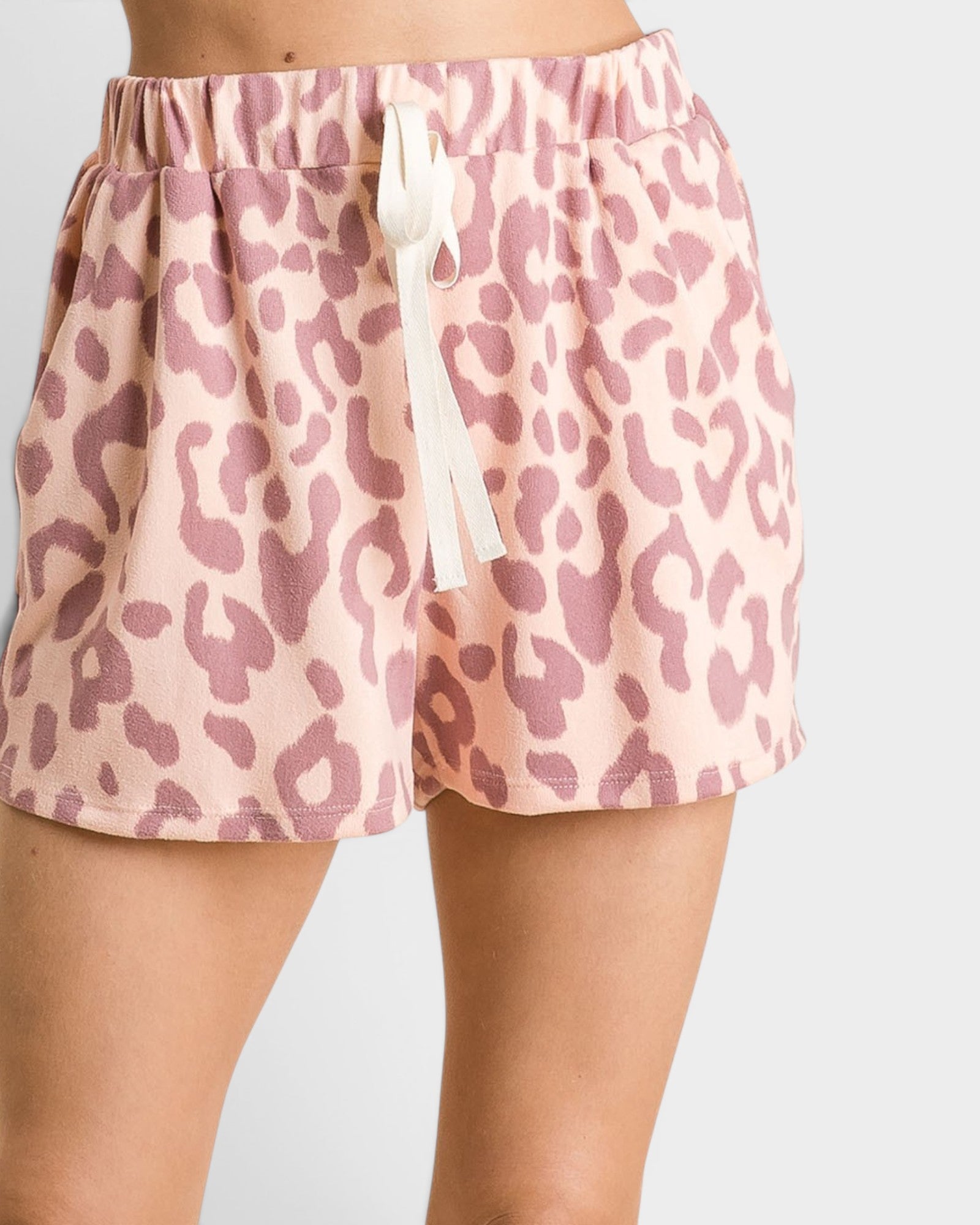 Pink leopard print shorts worn by a person on a light gray background