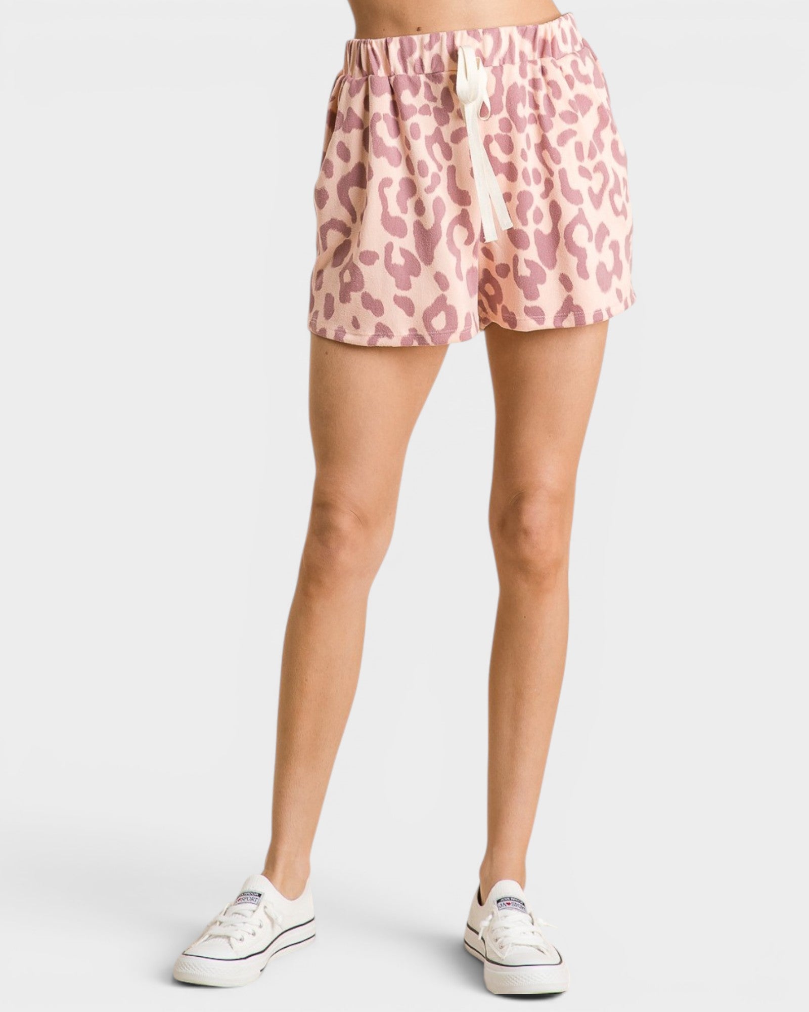Person wearing pink leopard print shorts on a white background