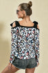 Woman wearing a leopard print top with black shoulder straps on a beige background