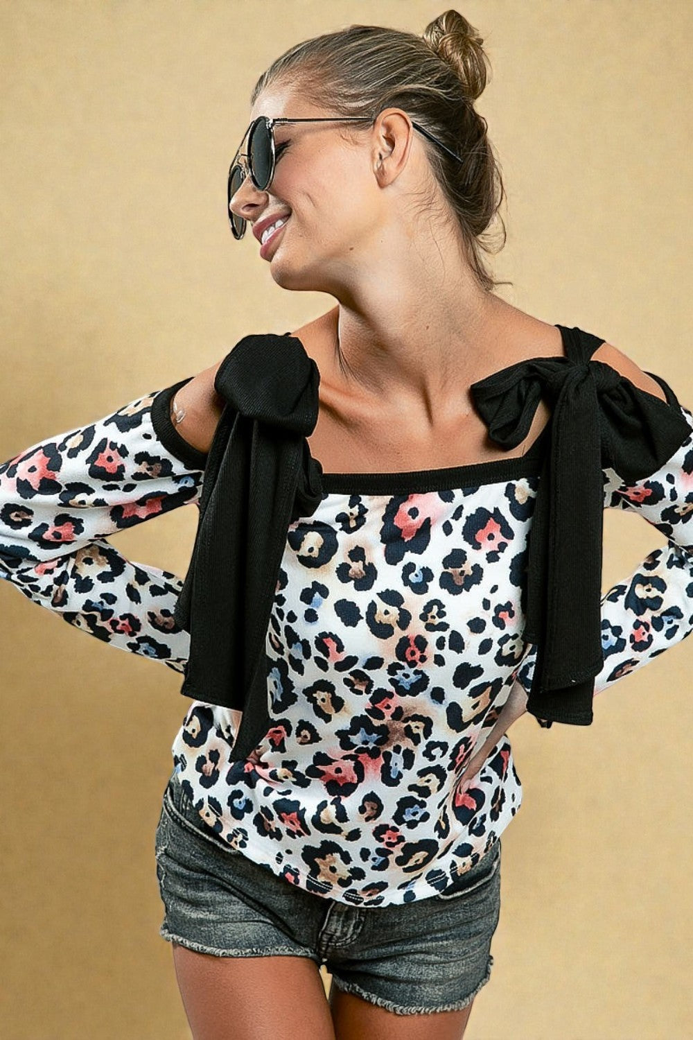 Woman wearing a leopard print top with black bow details on a beige background