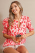 Woman wearing a pink and red patterned blouse holding a copper mug.