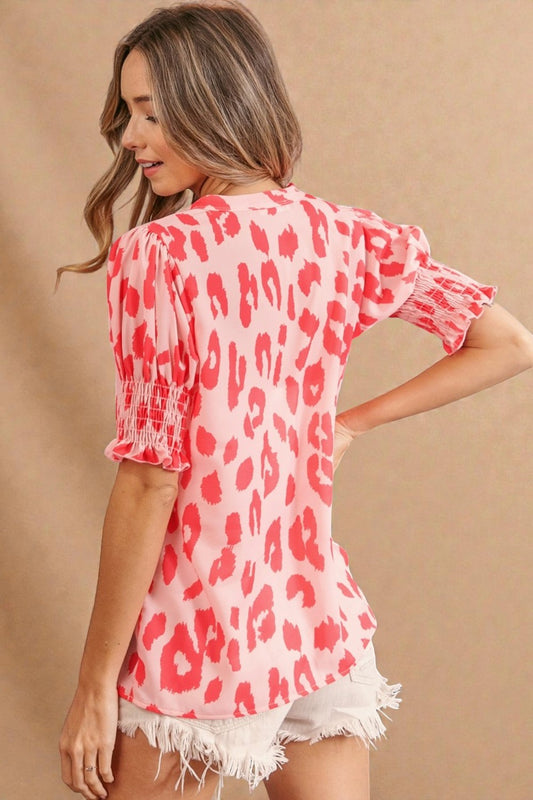 Woman wearing a pink leopard print top with white shorts on a beige background