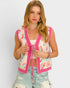 Woman wearing a patterned cardigan with pink trim against a plain background