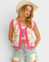Woman wearing a patterned cardigan, shorts, and a cowboy hat on a plain background