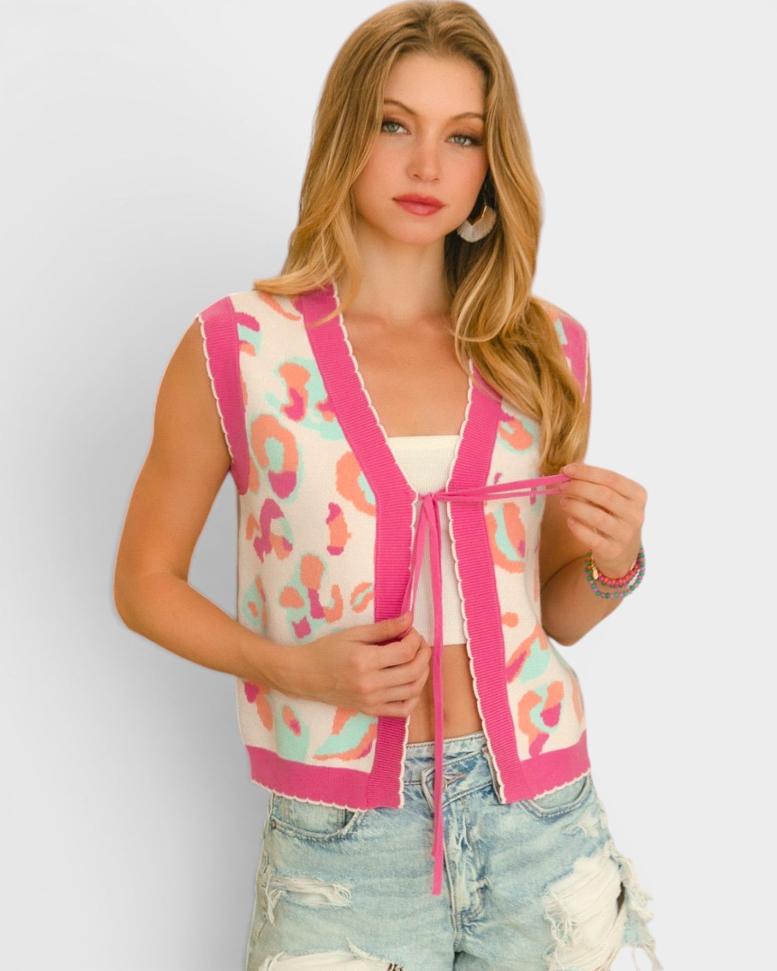 Woman wearing a colorful vest with pink accents on a plain background