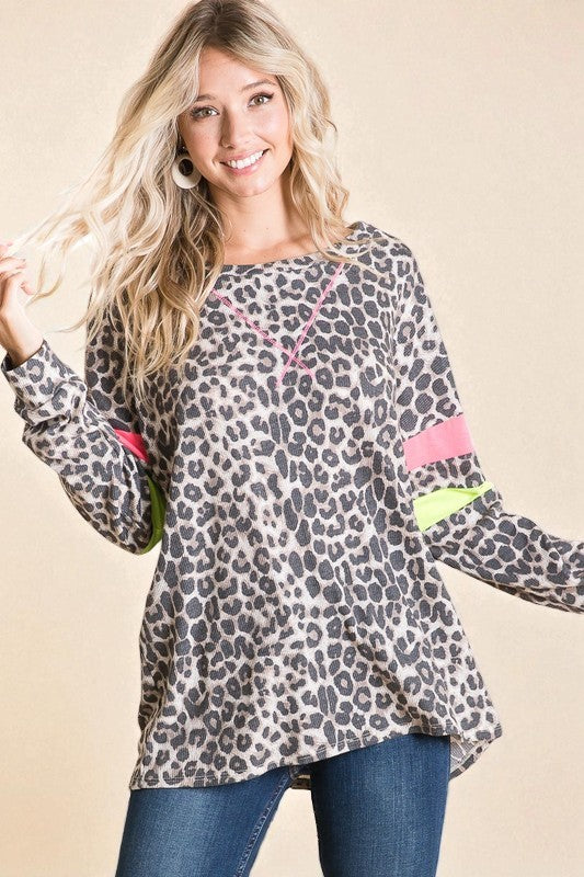 Woman wearing a leopard print long-sleeve top with colorful accents on a beige background