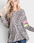 Woman wearing a leopard print top with colorful accents on a plain background