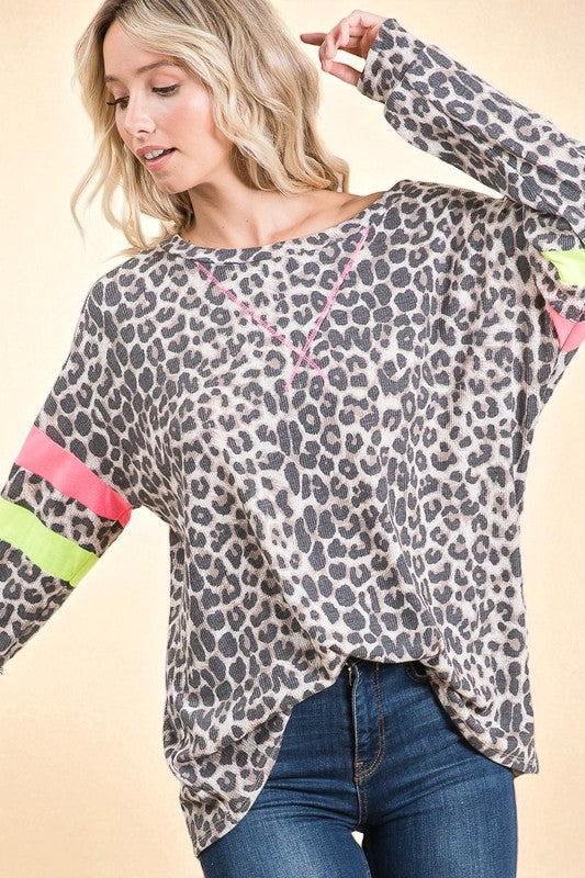 Woman wearing a leopard print long-sleeve top with colorful sleeves on a beige background