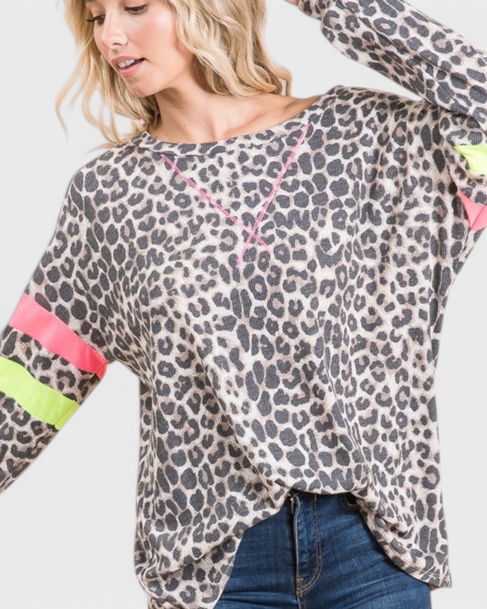 Woman wearing a leopard print top with colorful sleeves on a plain background
