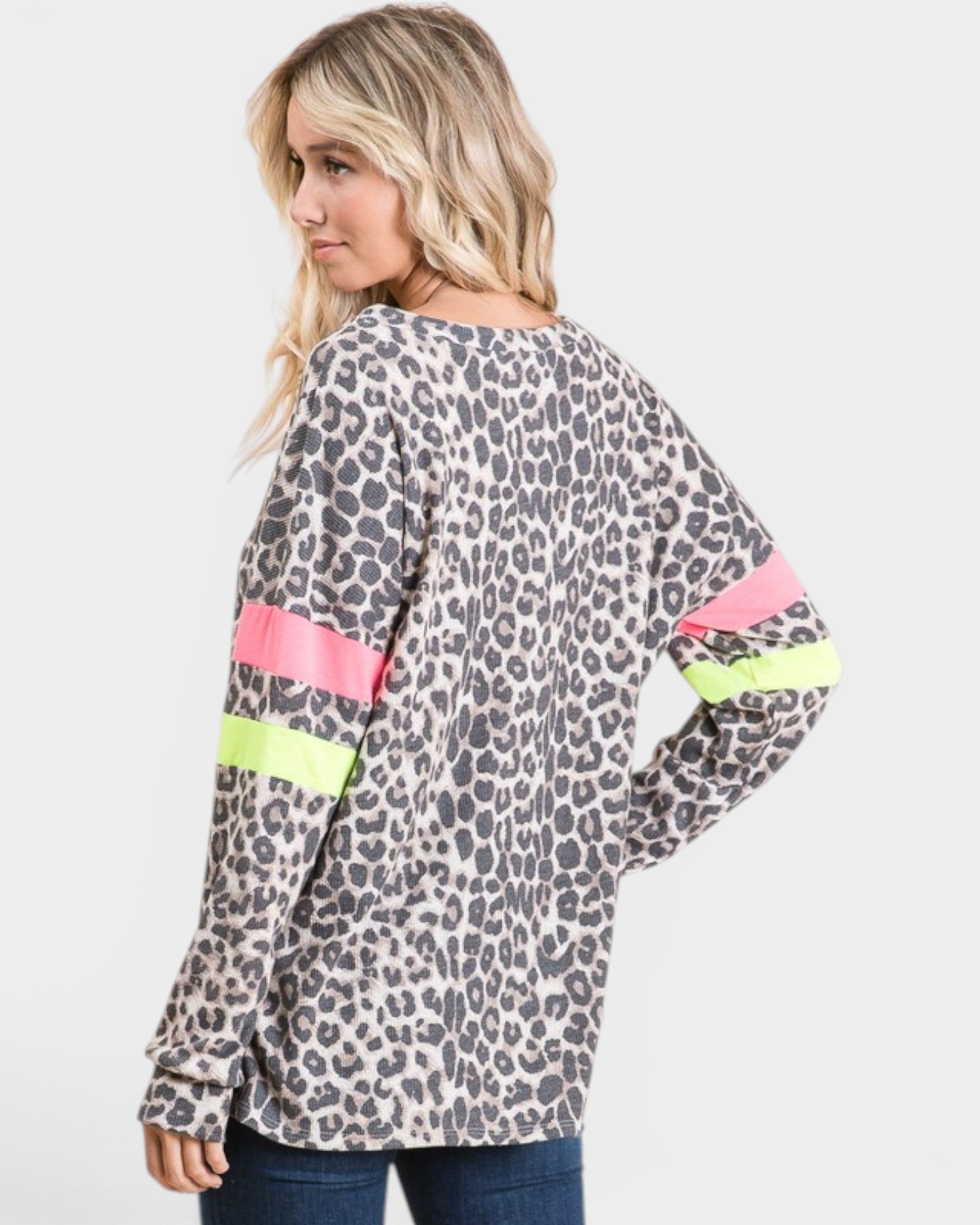 Woman wearing a leopard print top with colorful sleeves on a light gray background