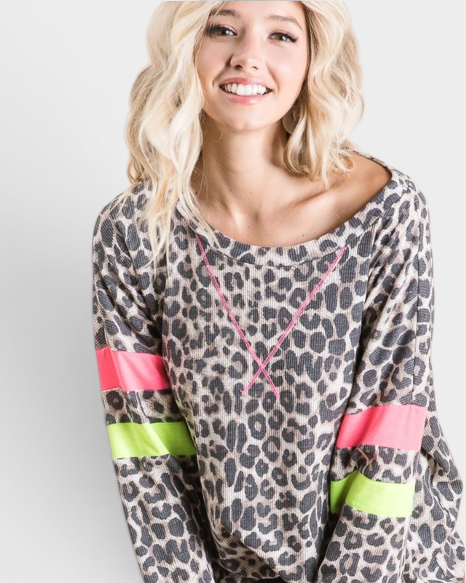 Woman wearing a leopard print top with colorful sleeves against a plain background