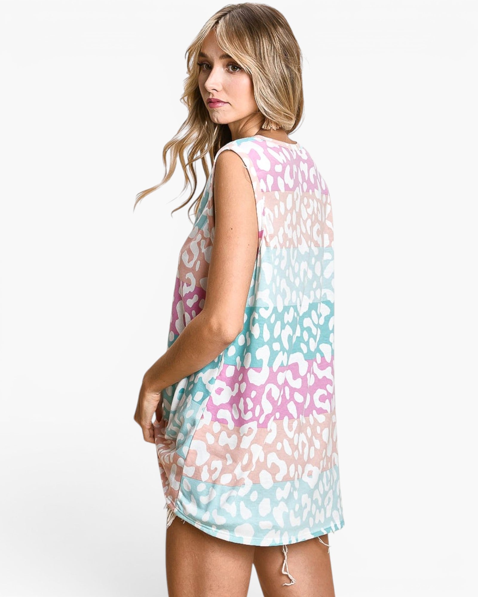 A woman modeling a sleeveless, loose-fit tunic dress with a pastel leopard print pattern in pink, mint green, and white, photographed against a clean white studio background.