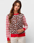 Woman wearing a leopard print and striped sweater with red accents on a plain background
