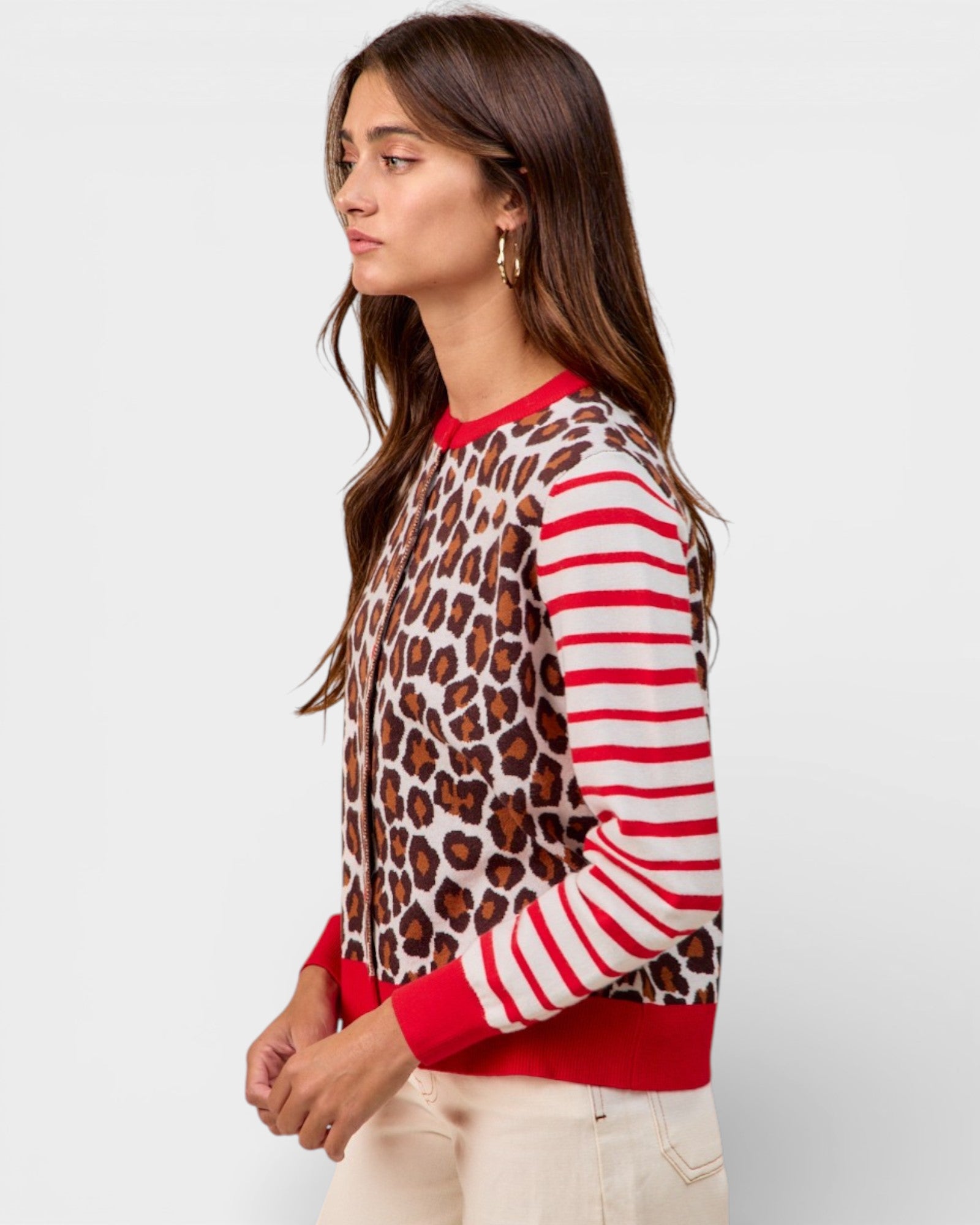 Woman wearing a sweater with leopard print and red stripes on a plain background