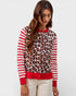Woman wearing a sweater with leopard print and red stripes on a white background