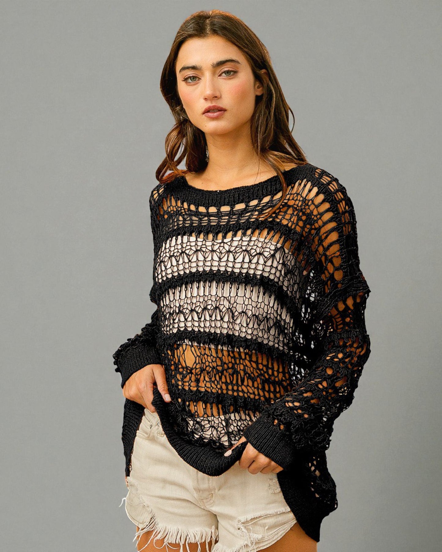 Woman wearing a black crochet sweater against a gray background