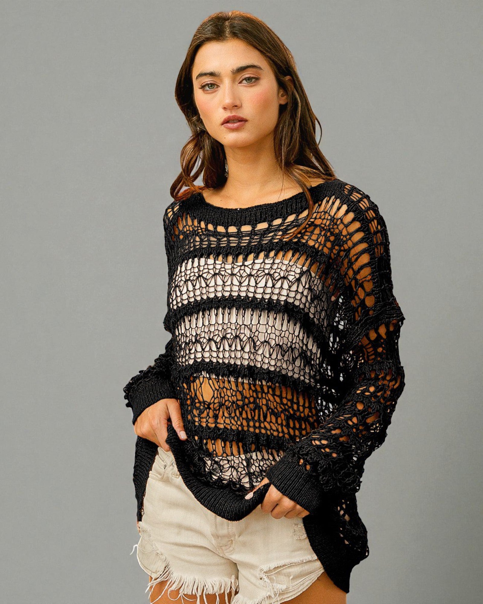 Woman wearing a black crochet sweater against a gray background