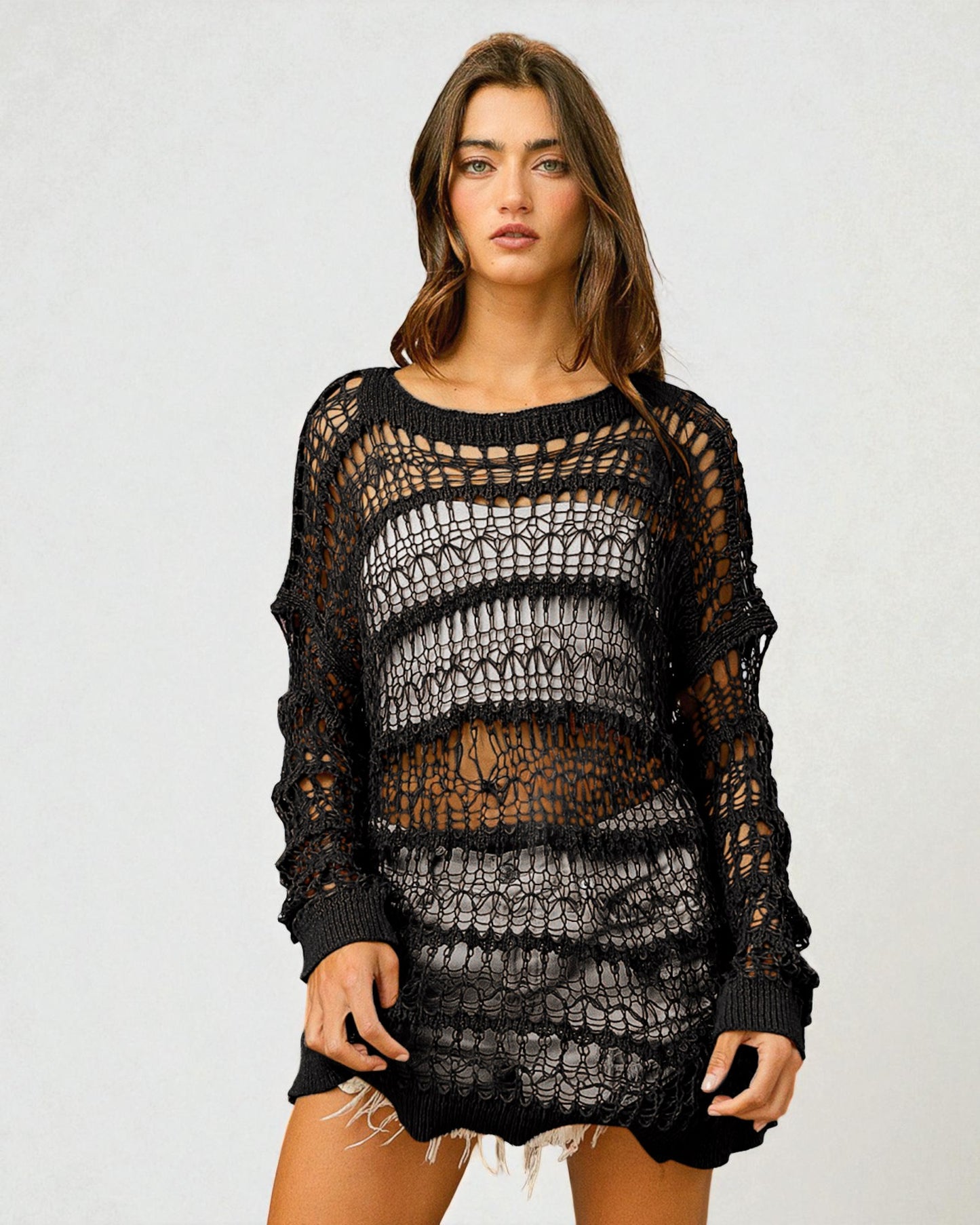 Woman wearing a black crochet dress against a plain background