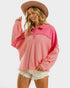 Woman wearing a pink long-sleeve shirt and white shorts with a brown hat on a white background