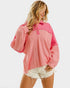 Woman wearing a pink sweatshirt and white shorts on a white background