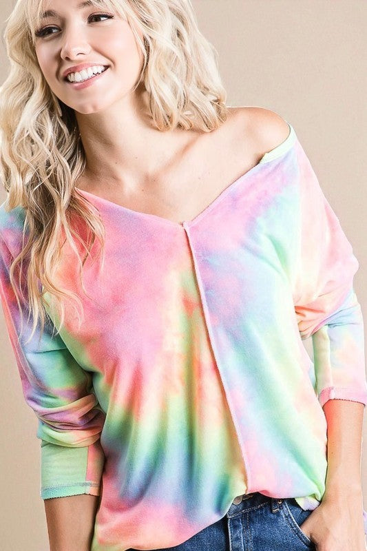 Woman wearing a colorful tie-dye top against a beige background