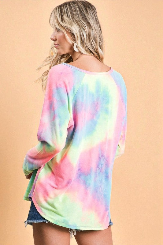 Person wearing a colorful tie-dye shirt against a beige background