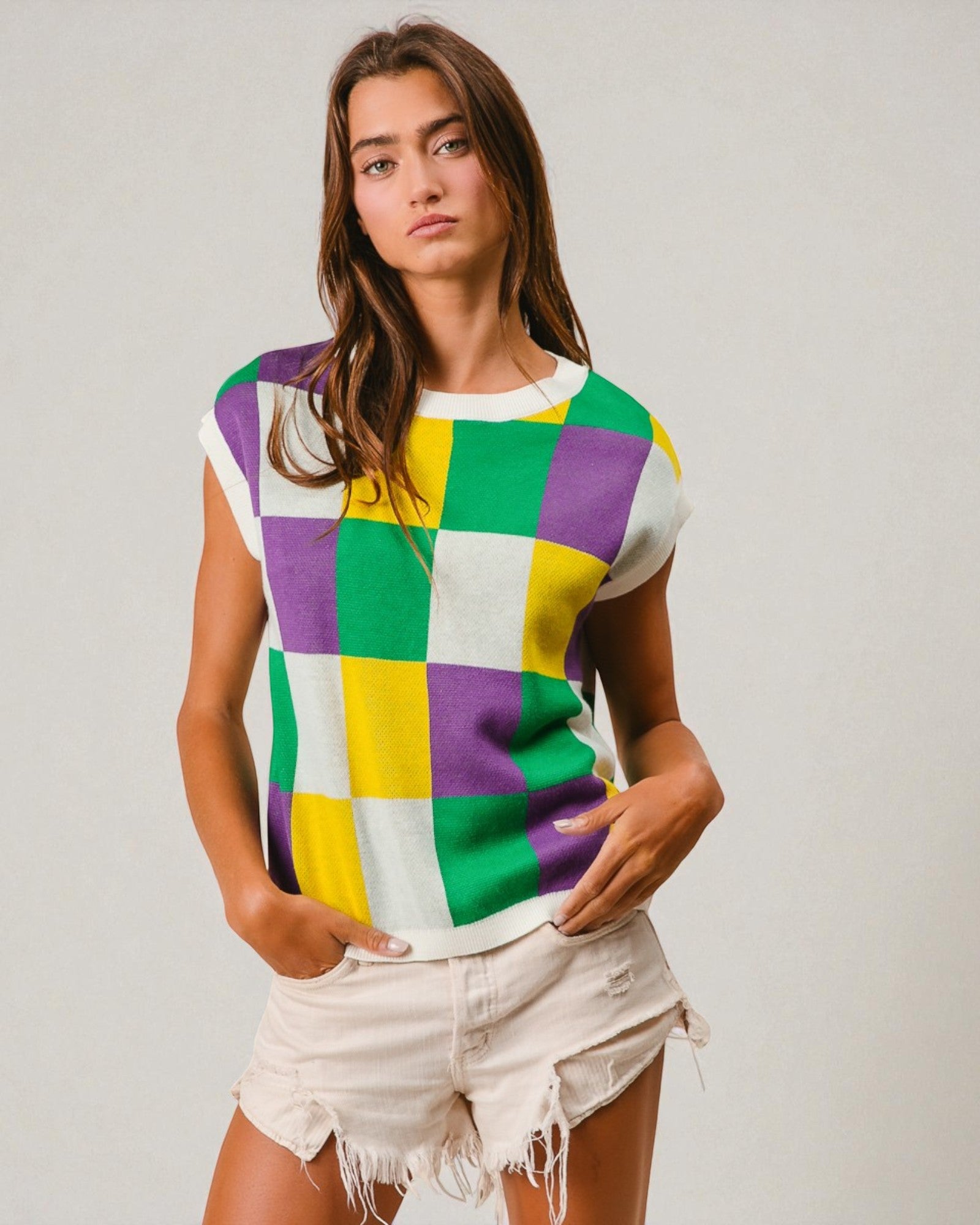 Woman wearing a colorful checkered shirt and denim shorts on a plain background