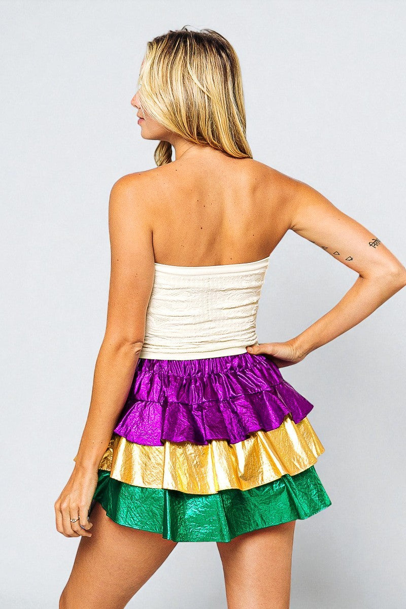 Woman wearing a colorful tiered skirt with a white top on a plain background