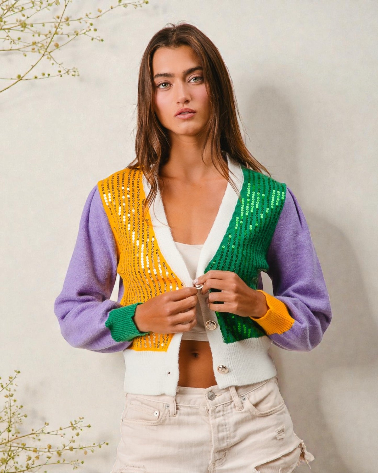 Woman wearing a colorful sequin cardigan against a neutral background