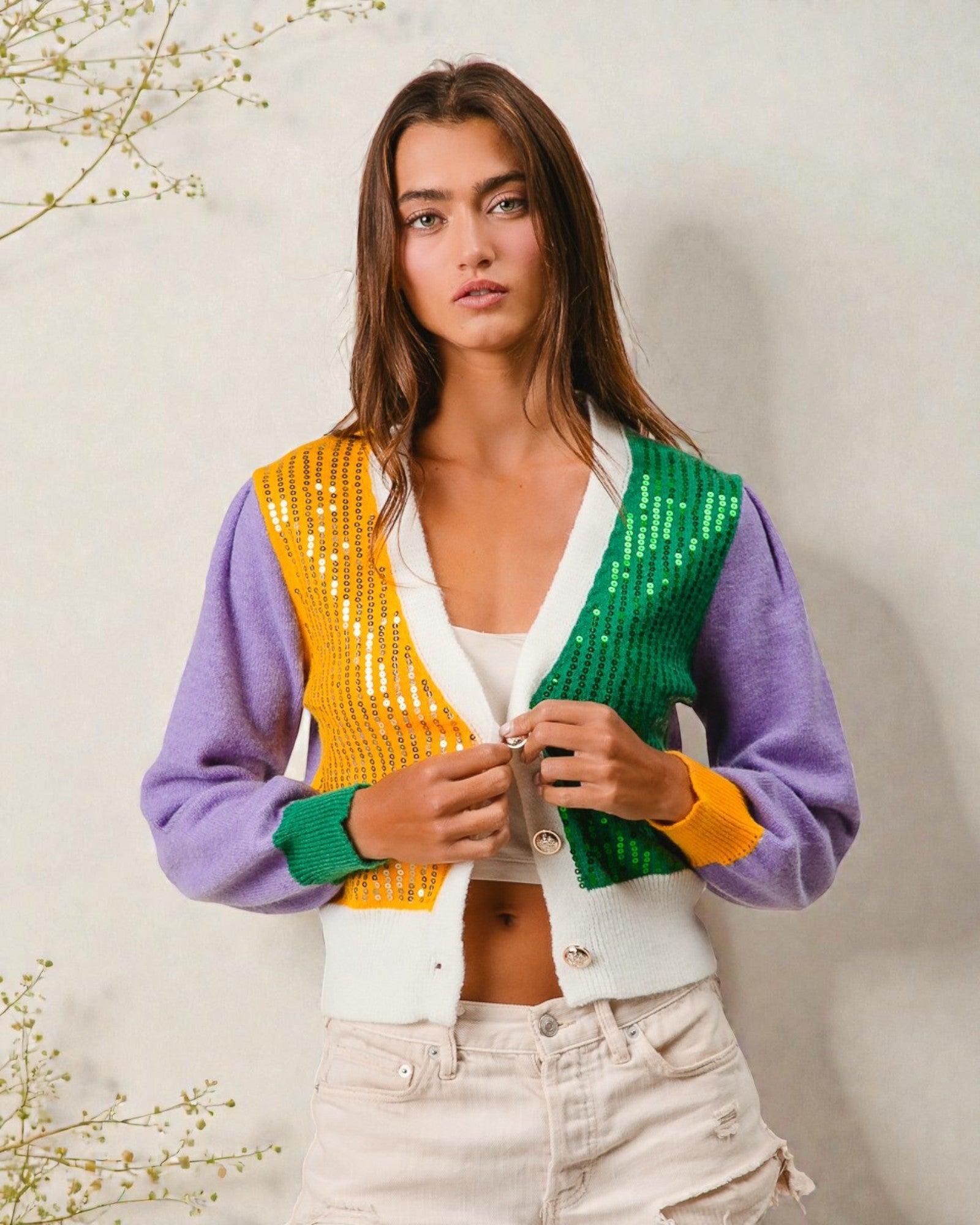 Woman wearing a colorful sequin cardigan against a neutral background