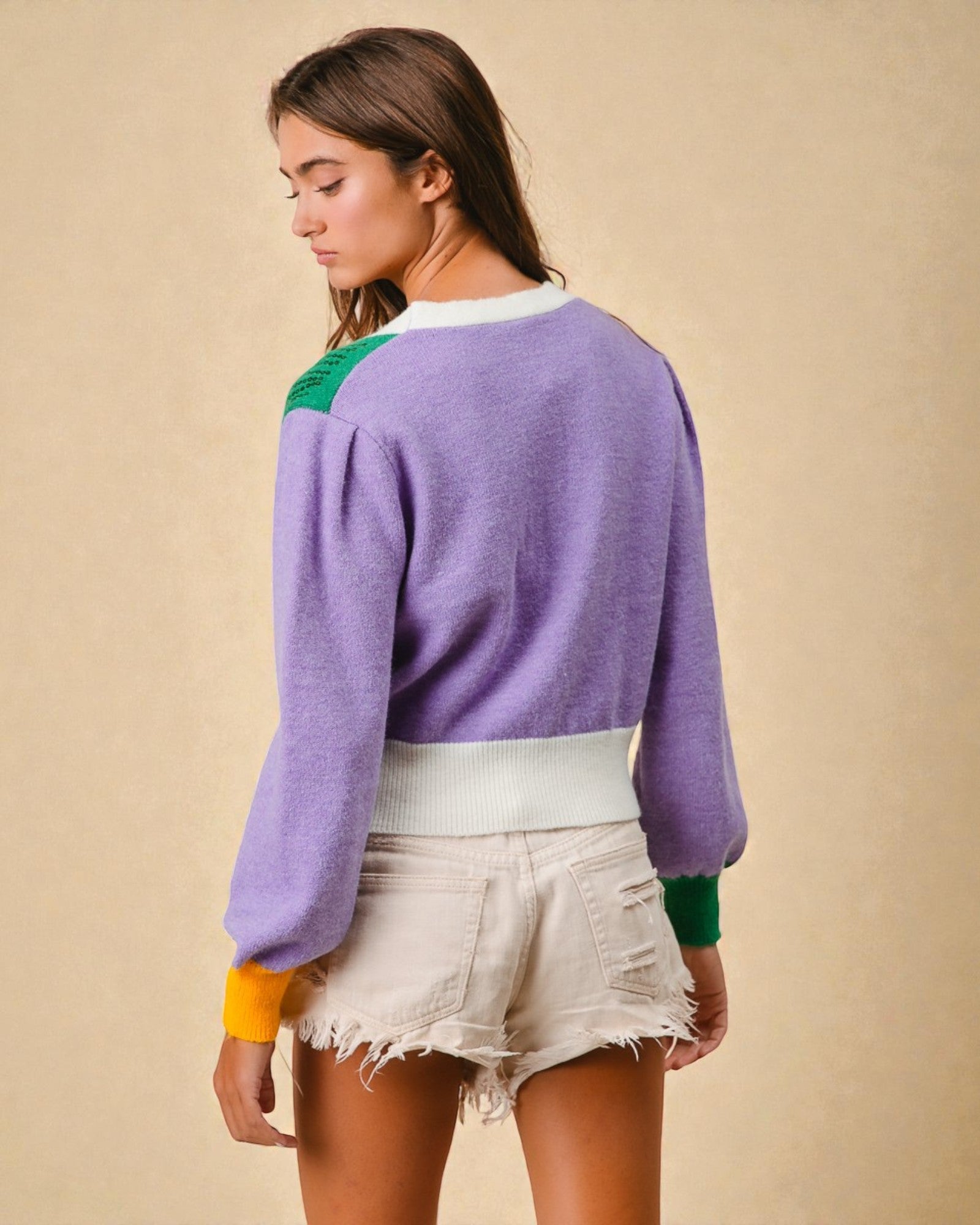Woman wearing a purple sweater with green accents on a beige background