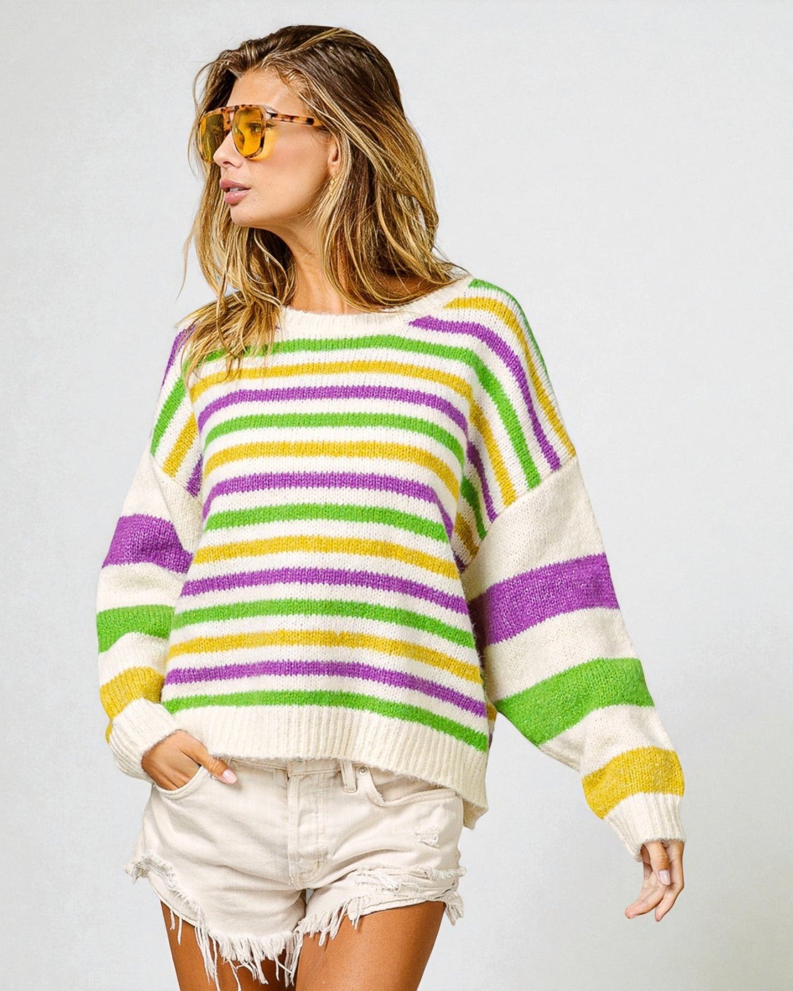 Woman wearing a colorful striped sweater and sunglasses on a plain background