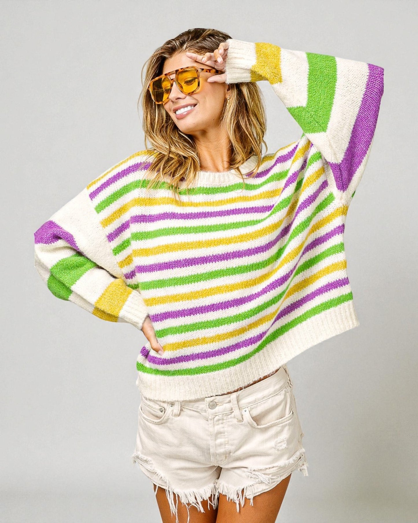 Woman wearing a colorful striped sweater and sunglasses on a gray background